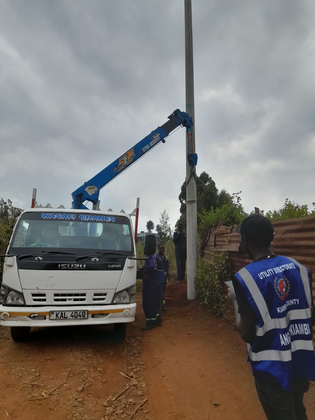 Crane truck raising a new street lighting pole along a road in Githunguri Township Ward