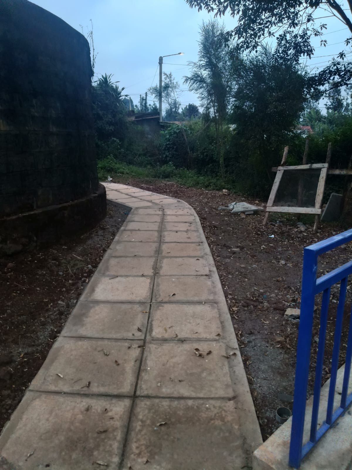 Paved access walkway leading to the Gathanji Dispensary with a street light overhead