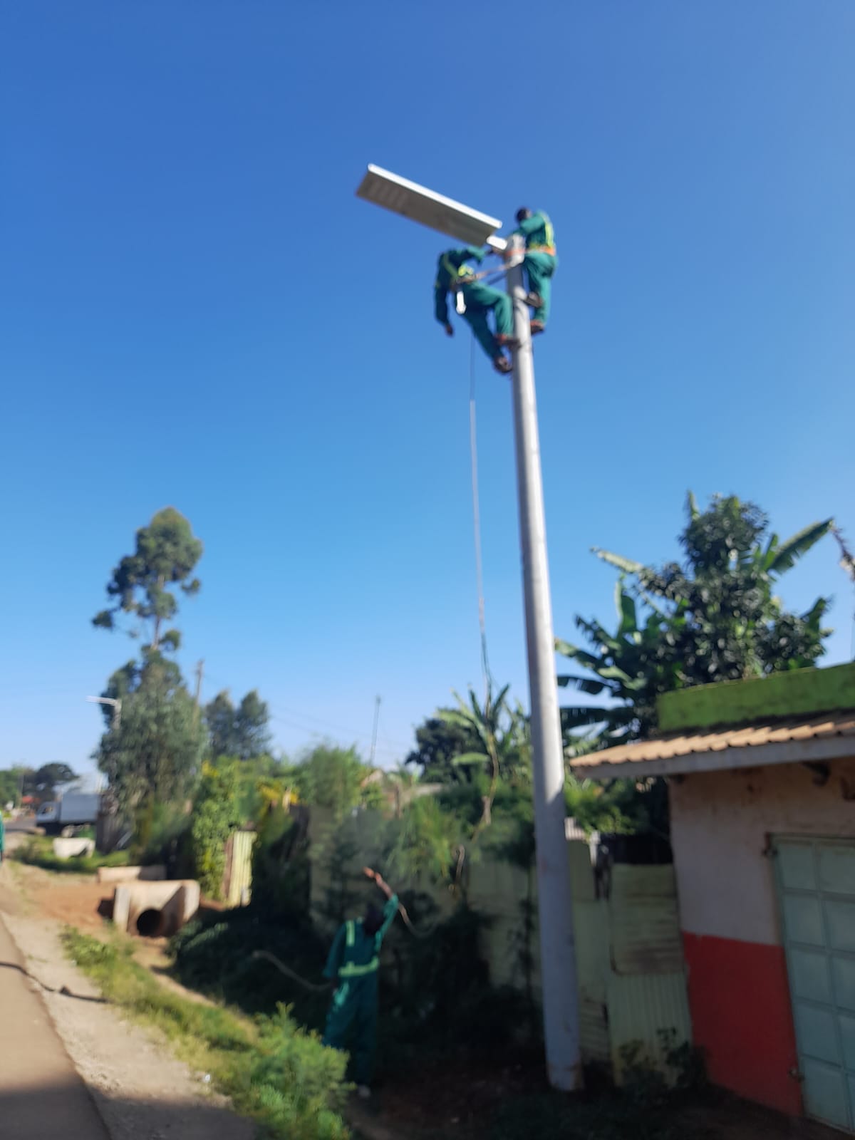 Maintenance crew working on a solar streetlight along a ward road