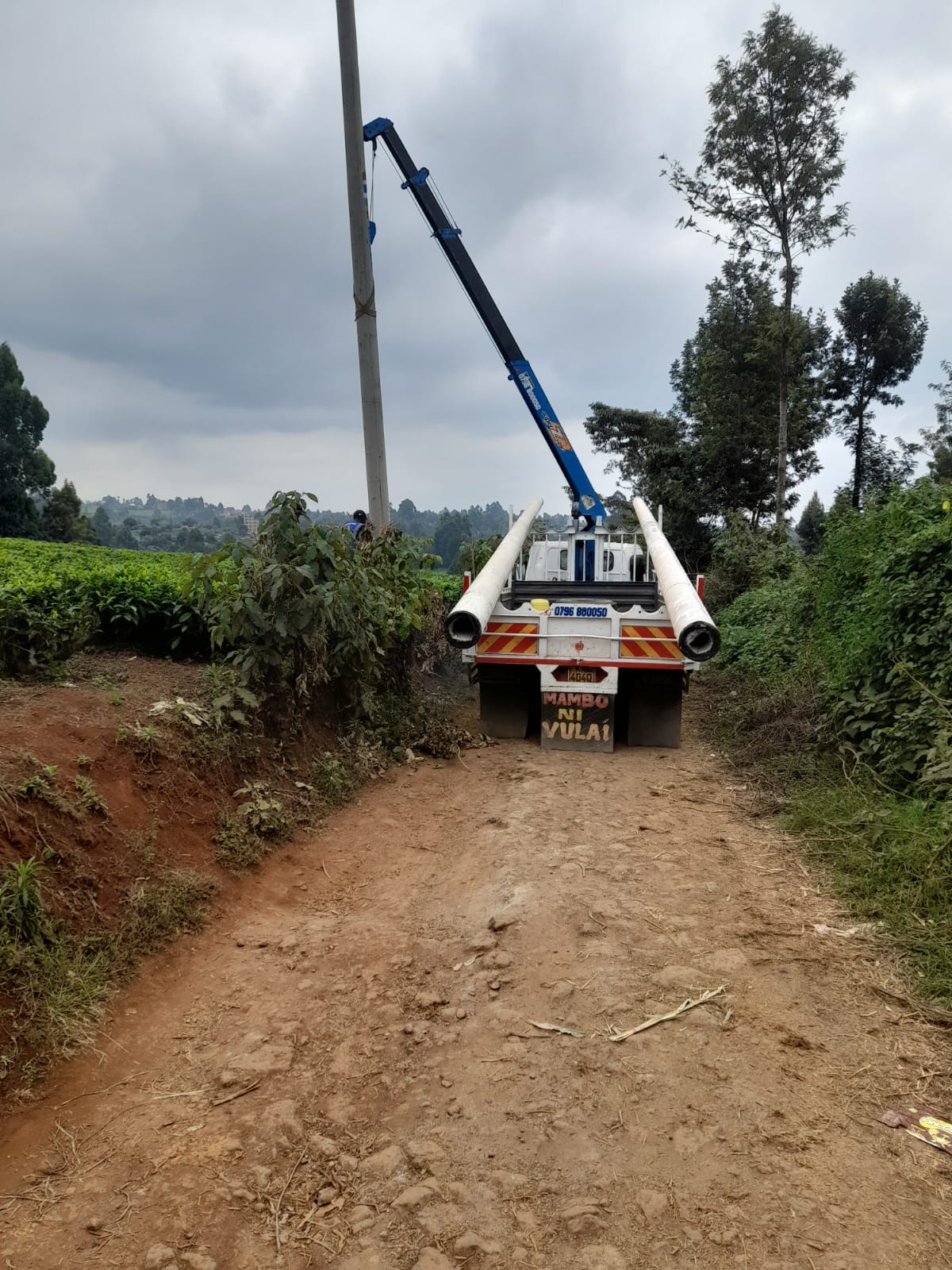 Crane truck delivering lighting poles on a rural access road